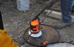 Bronze crucible being transferred to pouring shank
