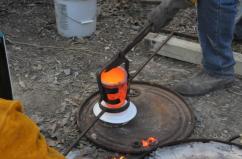 Bronze crucible being transferred to pouring shank