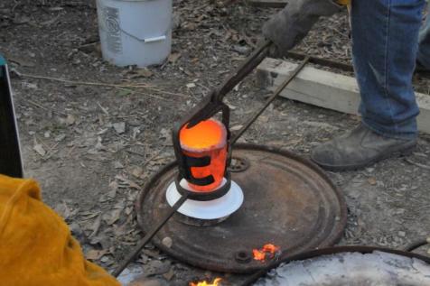 Bronze crucible being transferred to pouring shank