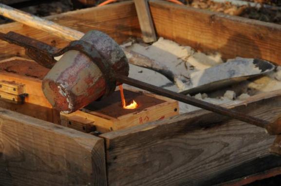 Pouring bronze into sand molds