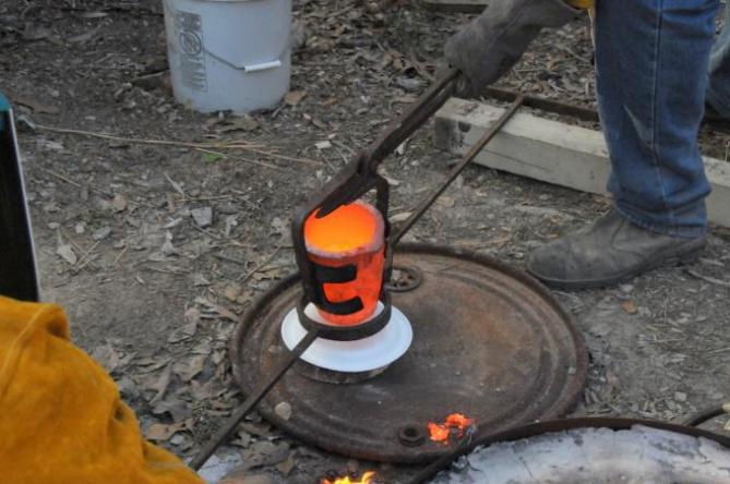 Bronze crucible being transferred to pouring shank
