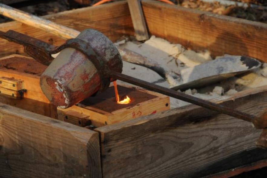Pouring bronze into sand molds